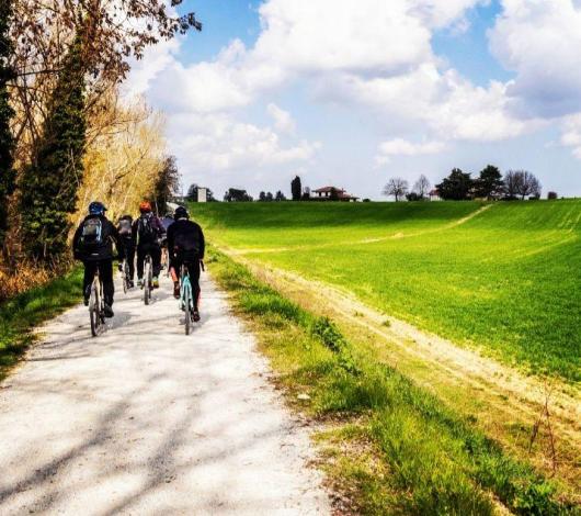 Ciclisti pedalano su un sentiero di campagna sotto un cielo sereno.