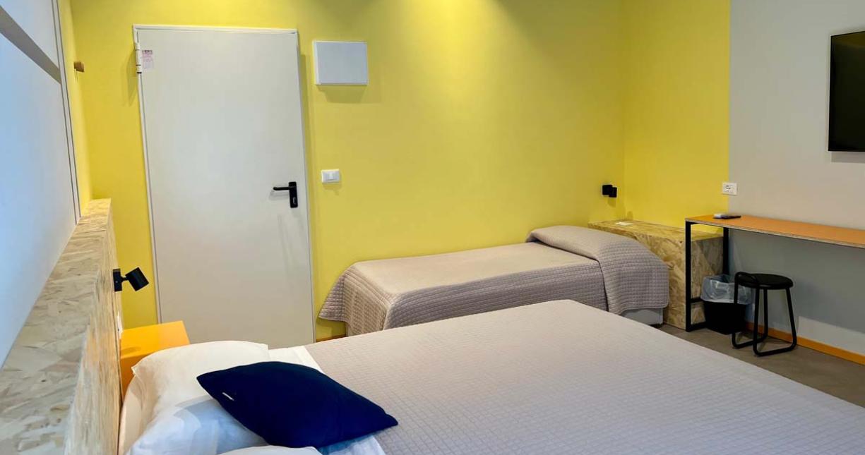 Camera luminosa, pareti gialle, letto confortevole, atmosfera accogliente e moderna.