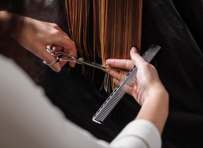 Taglio di capelli: parrucchiere usa forbici e pettine su capelli lisci e biondi.